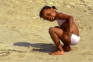 Kleinkind hockt am Strand